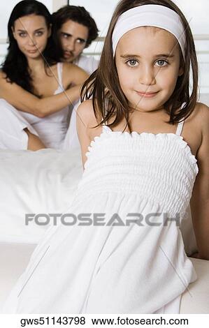 Close-up of a girl smiling with her parents sitting behind her View Large Photo Image Stock Photo - Close-up of a girl smiling with her parents sitting behind her. Fotosearch