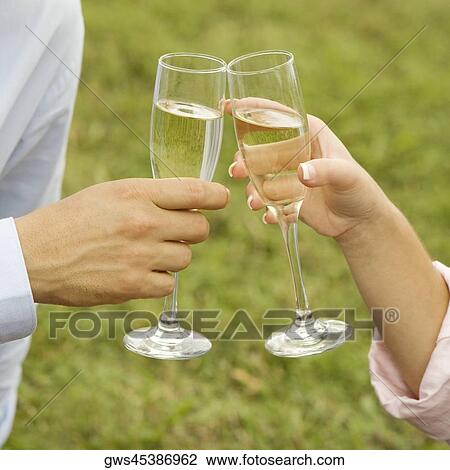 Stock Image - Close-up of a man and a woman toasting champagne flutes. Fotosearch