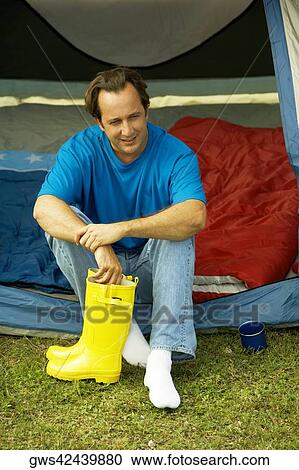 Close-up of a mature man sitting in a tent holding galoshes View Large Photo Image Stock Image - Close-up of a mature man sitting in a tent holding galoshes. Fotosearch
