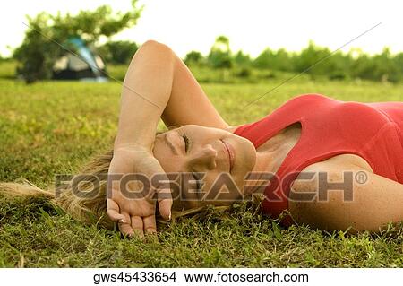 Picture - Close-up of a mature woman lying on the grass. Fotosearch