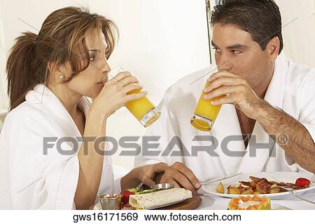 Close-up of a mid adult couple looking at each other drinking juice View Large Photo Image Stock Photo - Close-up of a mid adult couple looking at each other drinking juice. Fotosearch
