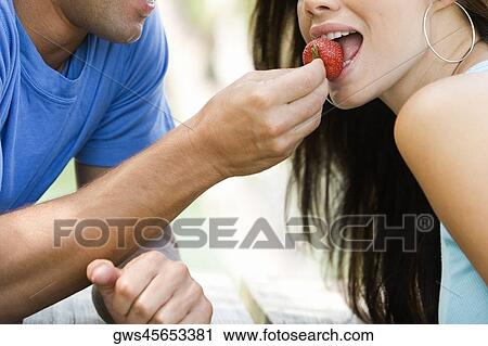 Close-up of a mid adult man feeding a young woman a strawberry View Large Photo Image Stock Image - Close-up of a mid adult man feeding a young woman a strawberry. Fotosearch
