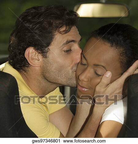 Stock Image - Close-up of a mid adult man kissing a young woman. Fotosearch