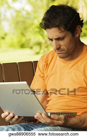 Close-up of a mid adult man looking at a laptop View Large Photo Image Stock Photography - Close-up of a mid adult man looking at a laptop. Fotosearch