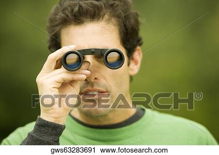 Close-up of a mid adult man looking through a pair of binoculars View Large Photo Image Stock Image - Close-up of a mid adult man looking through a pair of binoculars. Fotosearch