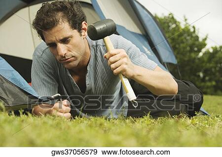 Stock Photo - Close-up of a mid adult man putting up a tent. Fotosearch