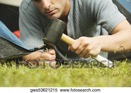 Stock Photography - Close-up of a mid adult man putting up a tent. Fotosearch