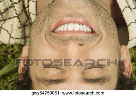 Stock Image - Close-up of a mid adult man sleeping on the grass. Fotosearch