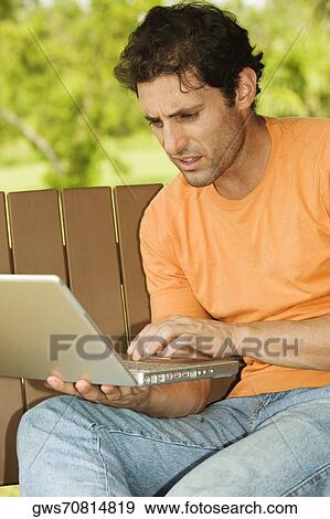 Close-up of a mid adult man using a laptop View Large Photo Image Stock Photo - Close-up of a mid adult man using a laptop. Fotosearch