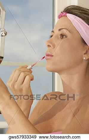 Close-up of a mid adult woman applying lip gloss View Large Photo Image Stock Photo - Close-up of a mid adult woman applying lip gloss. Fotosearch