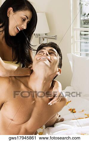 Stock Image - Close-up of a mid adult woman embracing a mid adult man on the bed. Fotosearch