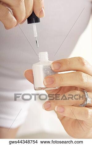 Close-up of a mid adult woman holding a bottle of nail polish View Large Photo Image Picture - Close-up of a mid adult woman holding a bottle of nail polish. Fotosearch