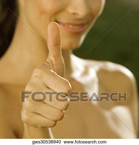 Stock Image - Close-up of a mid adult woman making a thumbs up sign. Fotosearch
