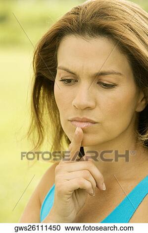 Stock Image - Close-up of a mid adult woman with her hand on her chin. Fotosearch