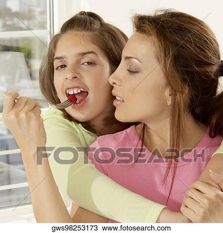 Stock Image - Close-up of a mother feeding her daughter strawberries. Fotosearch