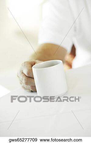 Stock Photo - Close-up of a person's hand holding a cup of coffee. Fotosearch