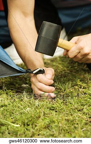 Stock Image - Close-up of a person's hand putting up a tent. Fotosearch