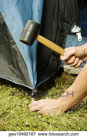 Stock Photo - Close-up of a person's hand putting up a tent. Fotosearch