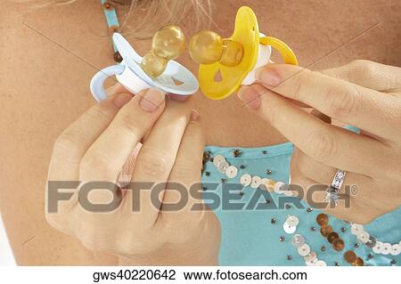 Close-up of a pregnant woman holding two pacifiers View Large Photo Image Stock Image - Close-up of a pregnant woman holding two pacifiers. Fotosearch