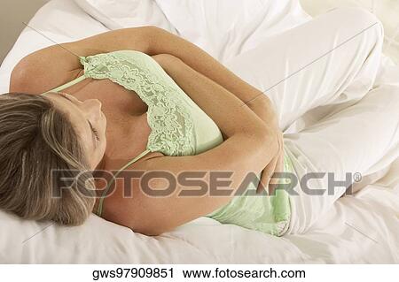 Close-up of a pregnant woman lying on the bed touching her abdomen View Large Photo Image Stock Image - Close-up of a pregnant woman lying on the bed touching her abdomen. Fotosearch