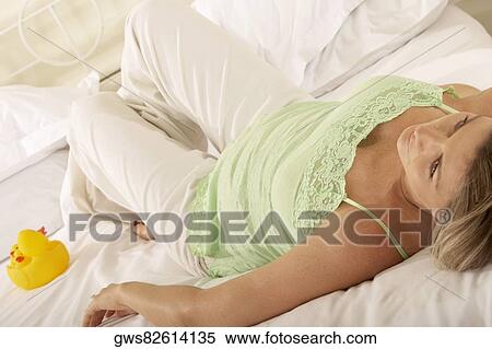 Stock Photography - Close-up of a pregnant woman lying on the bed. Fotosearch