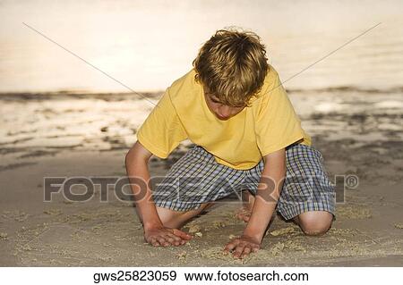 Close-up of a teenage boy playing in sand View Large Photo Image Stock Photo - Close-up of a teenage boy playing in sand. Fotosearch