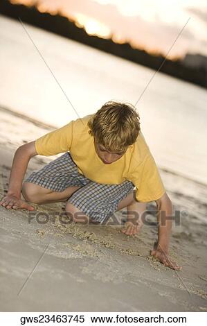 Stock Photography - Close-up of a teenage boy playing in sand. Fotosearch