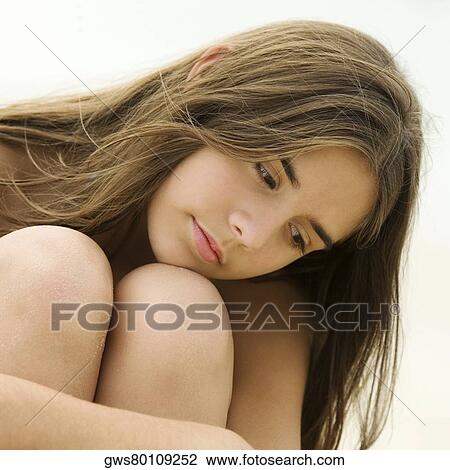 Stock Image - Close-up of a teenage girl sitting on the beach smiling. Fotosearch