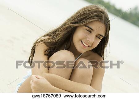 Close-up of a teenage girl sitting on the beach smiling View Large Photo Image Stock Photo - Close-up of a teenage girl sitting on the beach smiling. Fotosearch