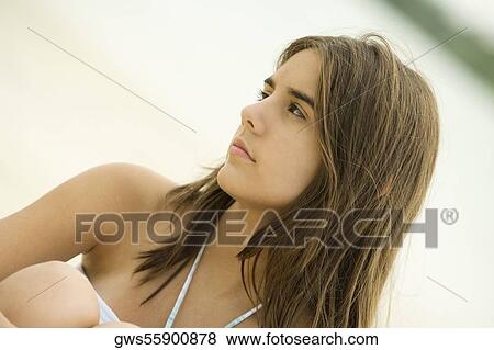 Close-up of a teenage girl sitting on the beach smiling View Large Photo Image Stock Photo - Close-up of a teenage girl sitting on the beach smiling. Fotosearch