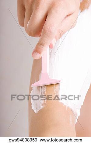 Stock Photo - Close-up of a woman's hand shaving her leg. Fotosearch