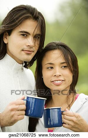 Stock Photography - Close-up of a young couple holding coffee cups. Fotosearch