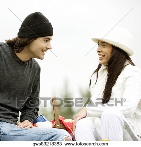 Close-up of a young couple sitting and smiling View Large Photo Image Stock Image - Close-up of a young couple sitting and smiling. Fotosearch
