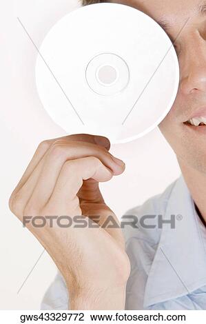 Close-up of a young man holding a CD in front of his eye View Large Photo Image Stock Image - Close-up of a young man holding a CD in front of his eye. Fotosearch