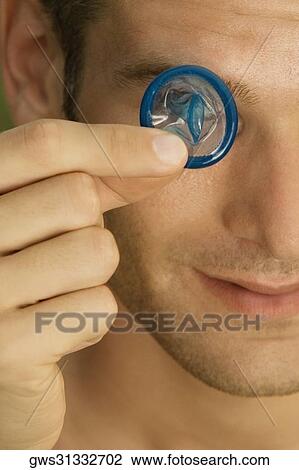 Close-up of a young man holding a condom in front of his eye View Large Photo Image Stock Image - Close-up of a young man holding a condom in front of his eye. Fotosearch