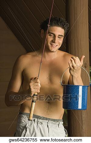Stock Photography - Close-up of a young man holding a fishing rod and a bucket. Fotosearch