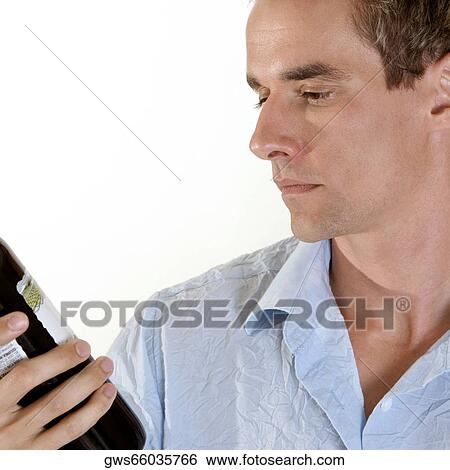 Close-up of a young man looking at a wine bottle View Large Photo Image Stock Photograph - Close-up of a young man looking at a wine bottle. Fotosearch