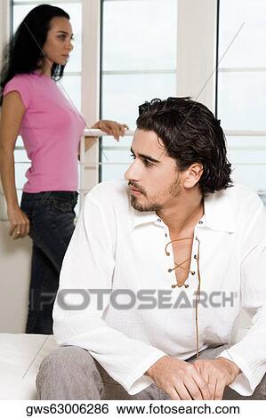 Close-up of a young man sitting with a young woman standing behind him View Large Photo Image Stock Photograph - Close-up of a young man sitting with a young woman standing behind him. Fotosearch