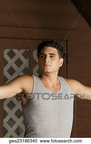 Close-up of a young man standing with his arms outstretched and looking away View Large Photo Image Stock Image - Close-up of a young man standing with his arms outstretched and looking away. Fotosearch