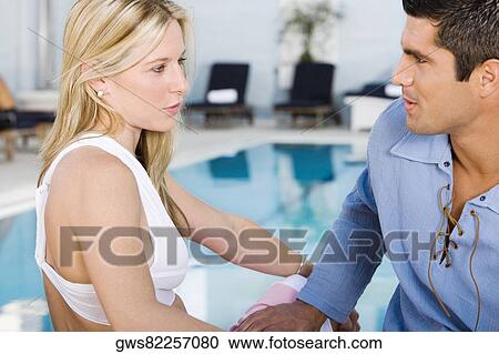 Stock Image - Close-up of a young woman and a mid adult man looking at each other. Fotosearch