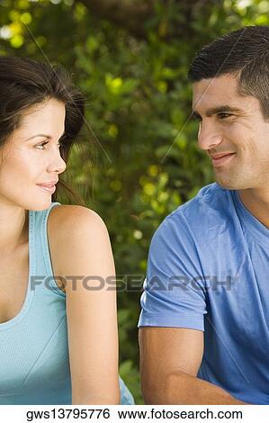 Stock Photograph - Close-up of a young woman and a mid adult man looking at each other. Fotosearch