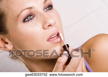 Close-up of a young woman applying lipstick View Large Photo Image Stock Image - Close-up of a young woman applying lipstick. Fotosearch