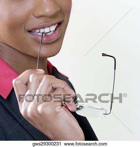 Close-up of a young woman biting the shaft of her eyeglasses View Large Photo Image Stock Image - Close-up of a young woman biting the shaft of her eyeglasses. Fotosearch