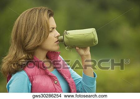 Picture - Close-up of a young woman drinking water from a water bottle. Fotosearch