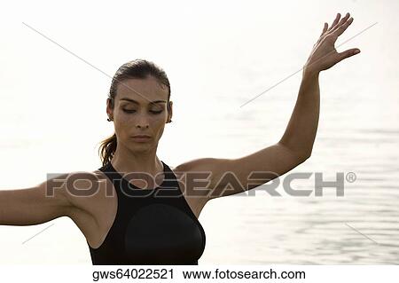 Stock Image - Close-up of a young woman exercising in a lake. Fotosearch