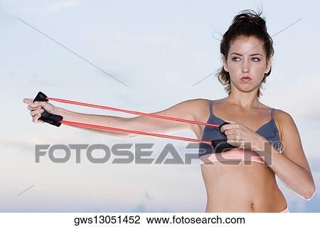 Stock Image - Close-up of a young woman exercising with a resistance band. Fotosearch