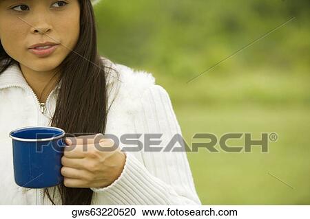 Stock Image - Close-up of a young woman holding a cup of coffee. Fotosearch