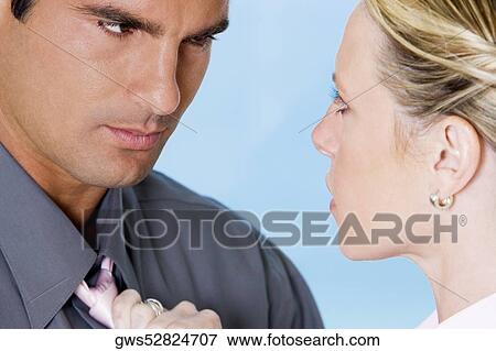 Close-up of a young woman holding a mid adult man by his tie View Large Photo Image Stock Photo - Close-up of a young woman holding a mid adult man by his tie. Fotosearch