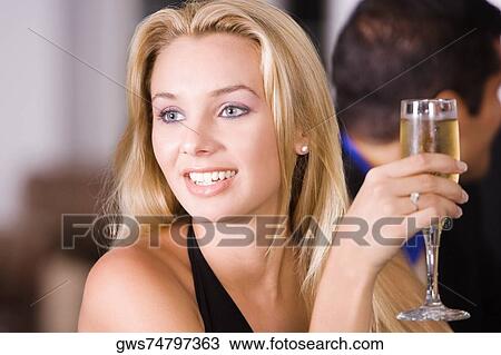 Close-up of a young woman holding a glass of champagne View Large Photo Image Stock Image - Close-up of a young woman holding a glass of champagne. Fotosearch