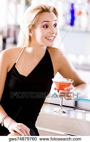 Stock Image - Close-up of a young woman holding a glass of martini. Fotosearch